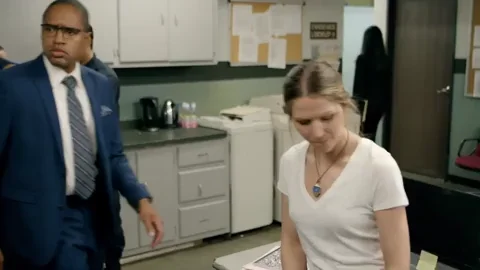 Bureau — homme passe, femme a l'air frustrée/agacée