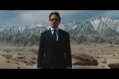 Tony Stark (Robert Downey Jr) in suit walking away from explosion in desert without looking back, Iron Man iconic scene