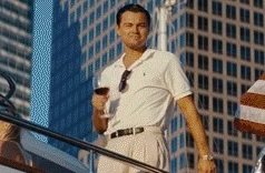 Leonardo DiCaprio standing on yacht/balcony with skyscrapers behind, white polo, drink in hand, confident downward gaze, Wolf of Wall Street