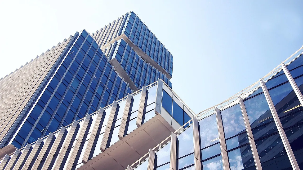 A low-angle shot of modern glass and concrete buildings against a clear sky.