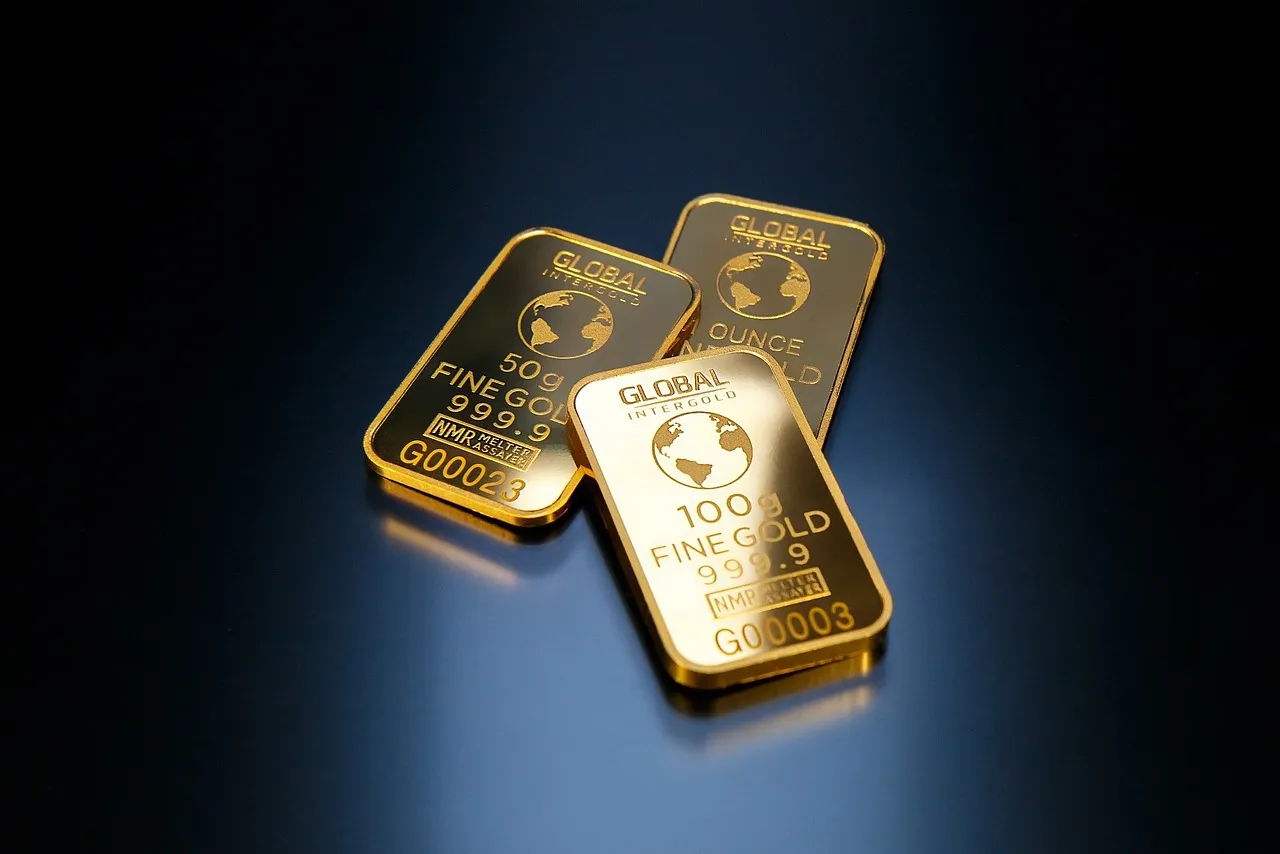 Three gold bars of different weights are displayed on a reflective dark surface.