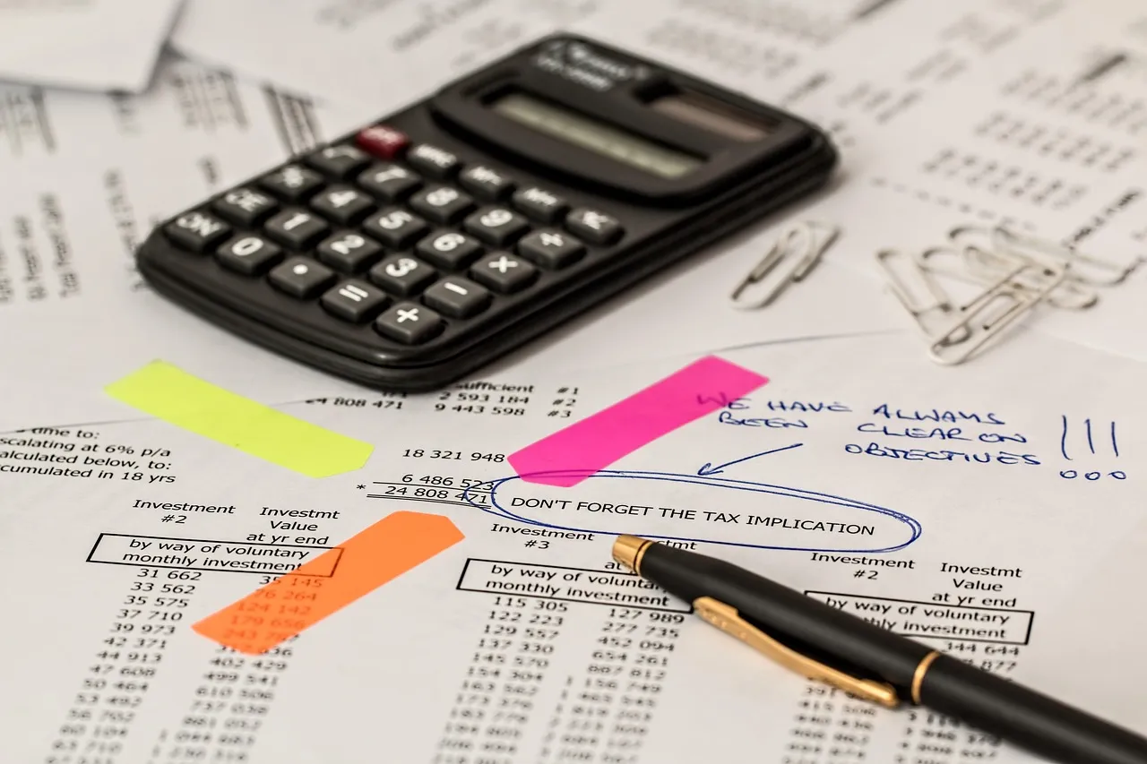 A calculator, pen, and paper with financial figures and notes, highlighting tax implications.