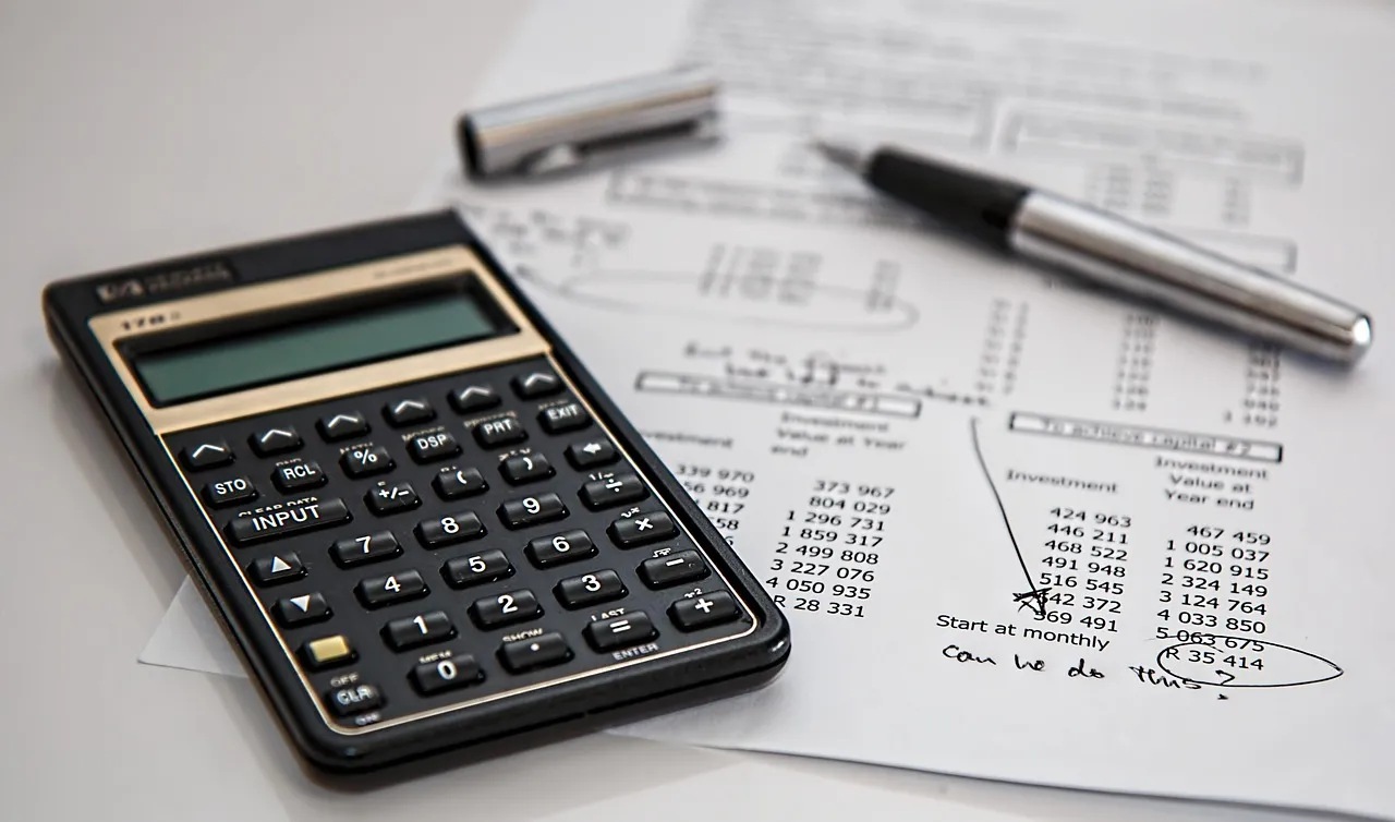 A calculator and pen rest on a financial document with handwritten notes.