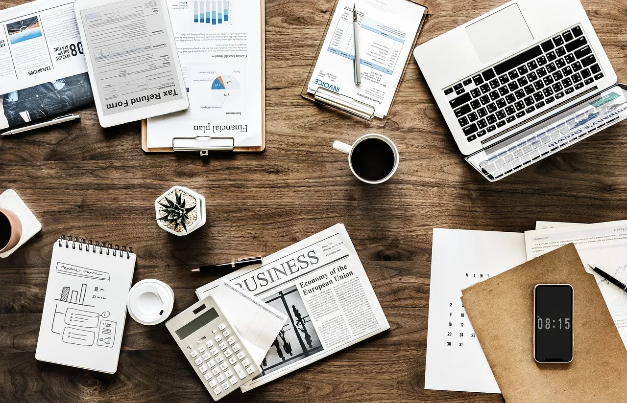 An overhead shot of a wooden desk with various business and finance-related items.
