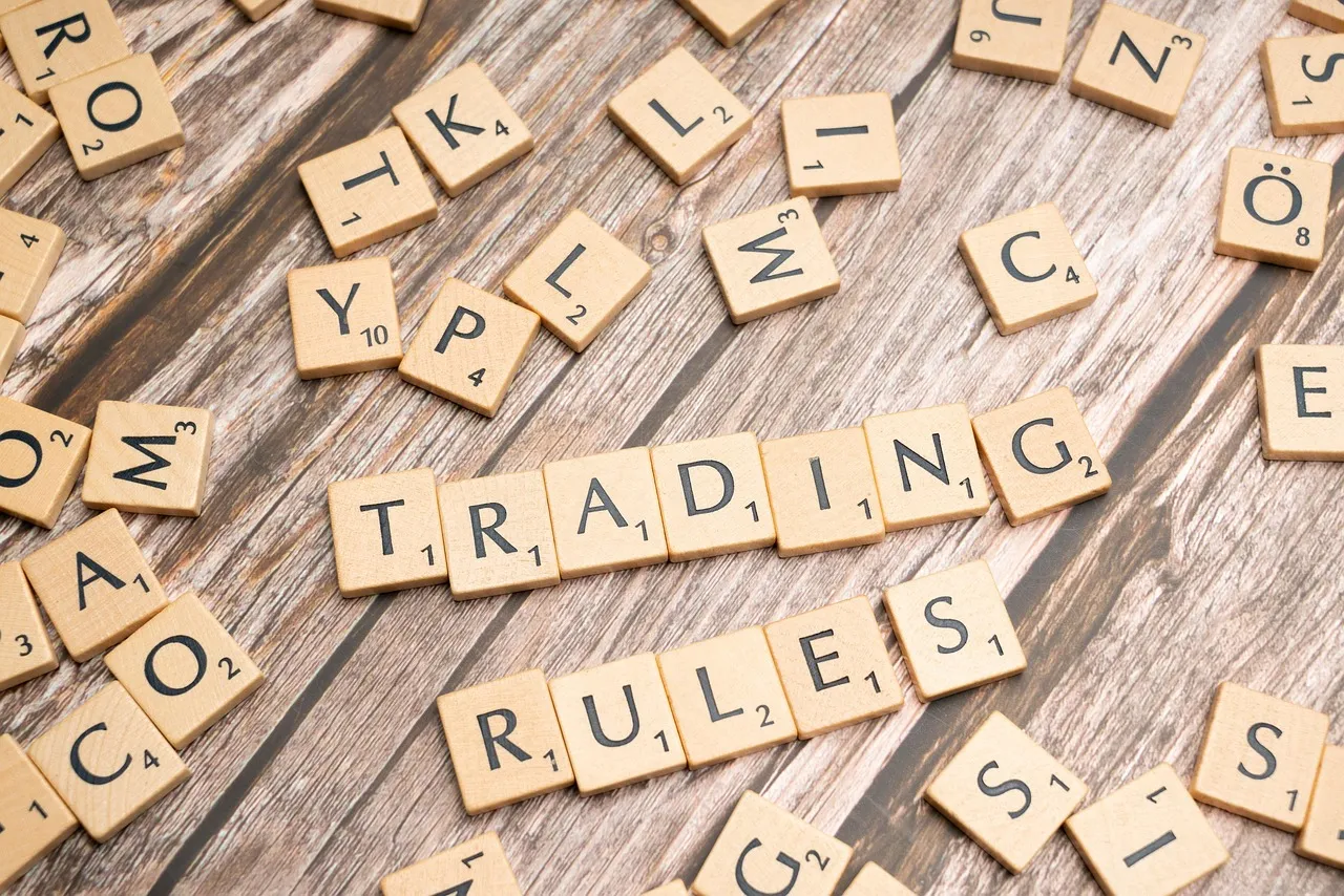 Scrabble tiles on a wooden surface spell out "TRADING RULES."